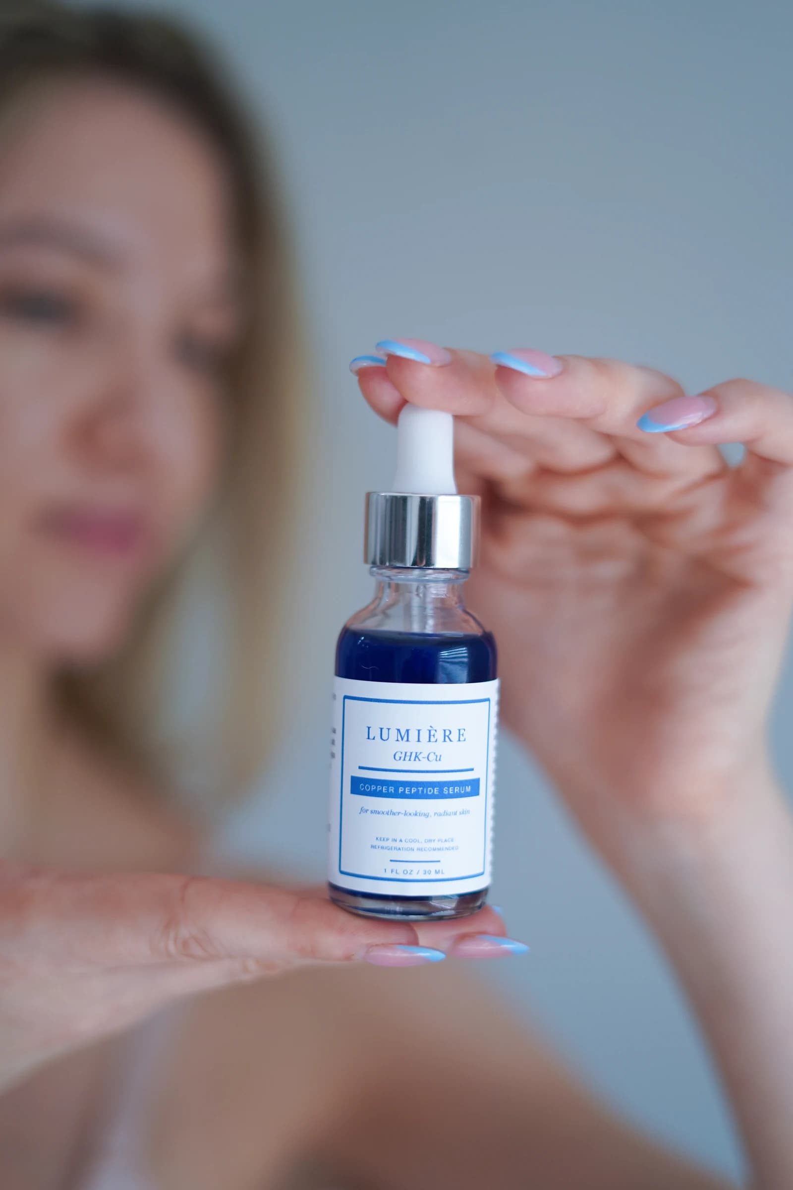 The Lumiere Routine serum held carefully between two hands